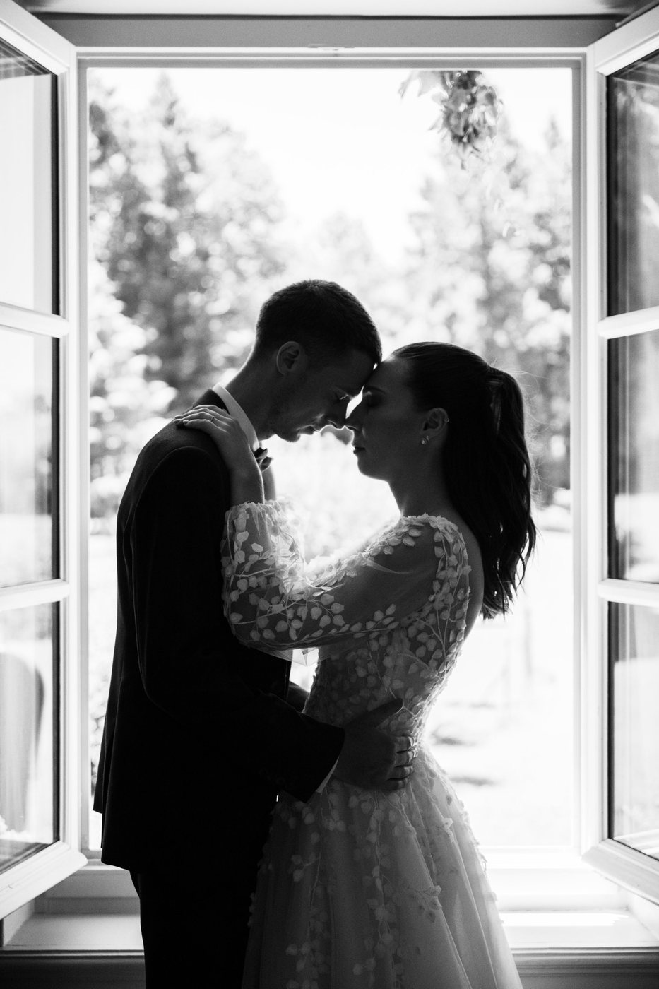 Couple front contre front, en silhouette devant une fenêtre ouverte, en noir et blanc